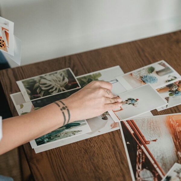 Folk&Curious : Team building atelier collage. Personne sélectionnant des photos d'inspiration pour un mood board sur une table en bois.