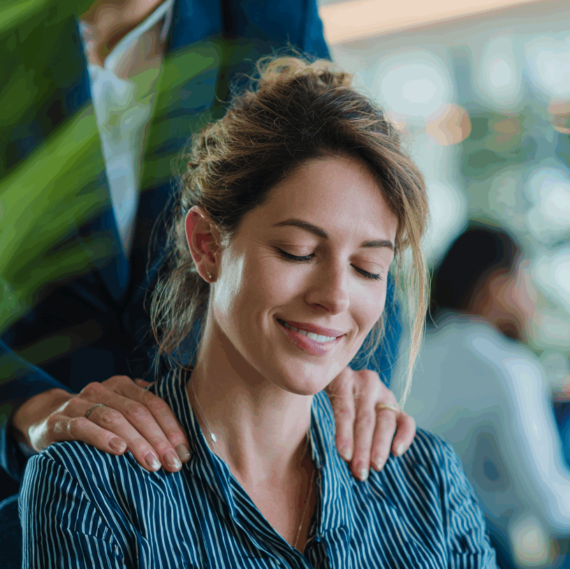Folk&Curious : bien-être et qualité de vie au travail (QVT). Collaboratrice détendue recevant un massage sur chaise lors d'un séminaire d'entreprise.
