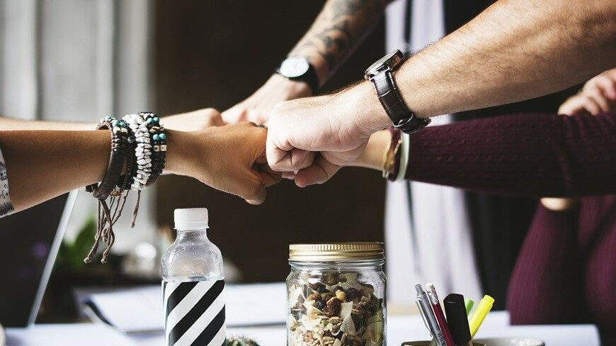 Folk&Curious : team building pour entreprise. Poings de collaborateurs joints en signe de cohésion et de succès.