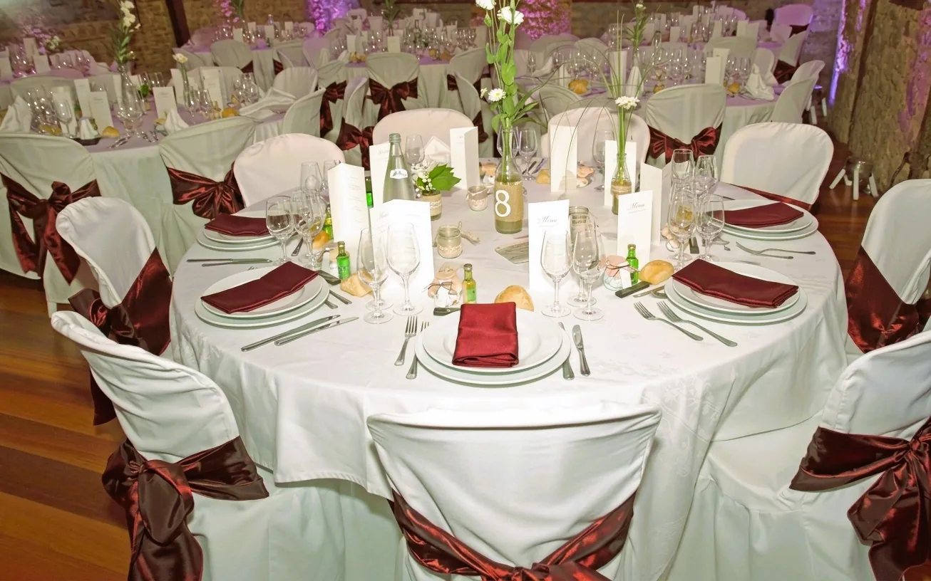 Tables de mariage dressées avec nœuds de chaise bordeaux